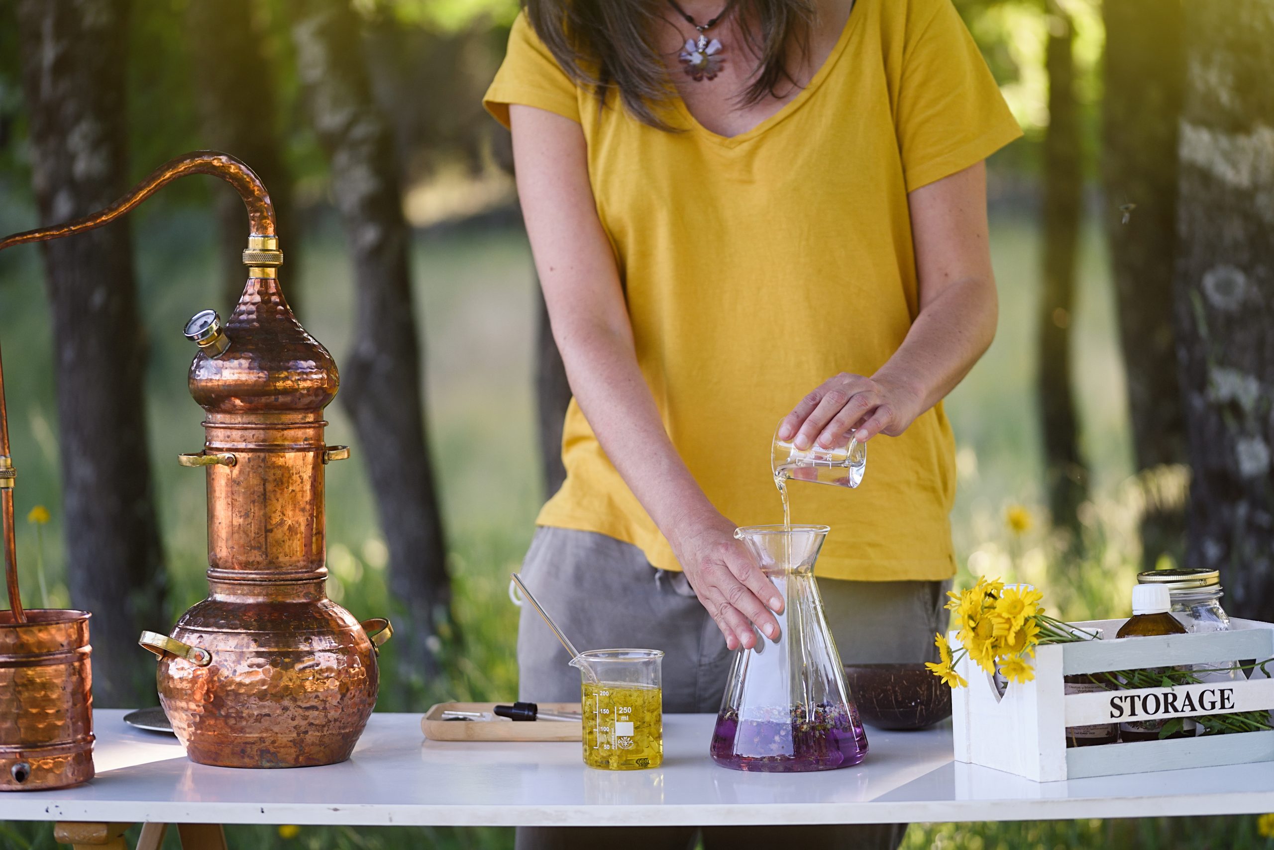 Lady distilling and preparing essential oils on table outdoors